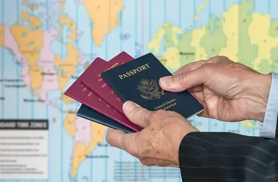 Person holding multiple passports in front of a world map.