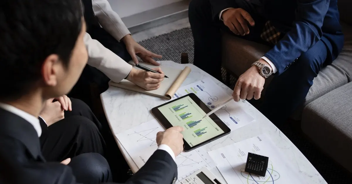 Professionals analyzing documents and data on a tablet while discussing offshore trusts and long term wealth structures.