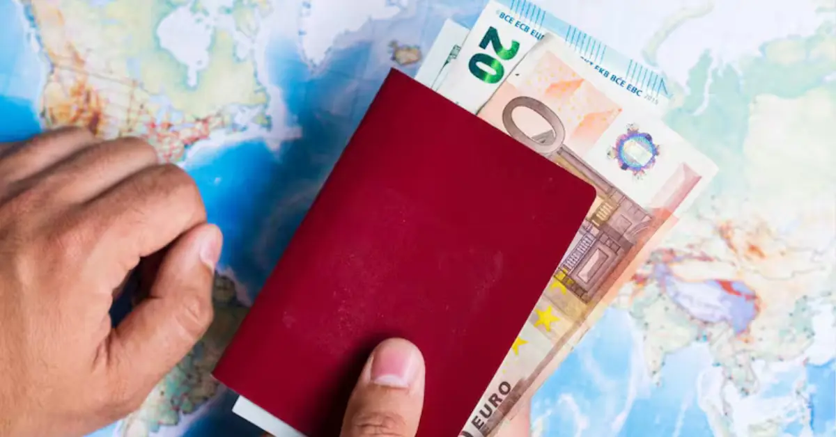Señor sosteniendo pasaporte con dinero sobre un mapamundi